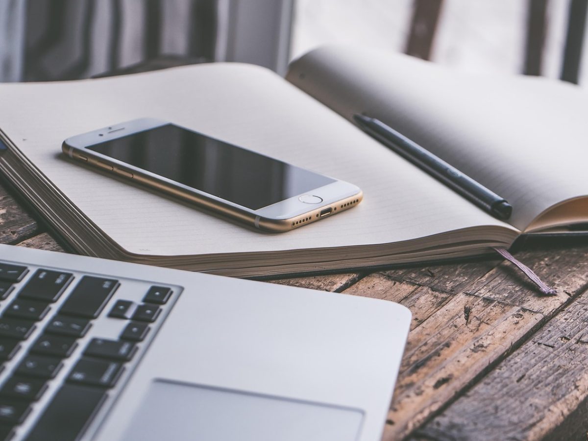 kanju3ai 内容编辑部的工作台，木质长桌上摊开写满剧集分集笔记的便签与两台显示器，午后的自然光斜照进来，氛围安静专注